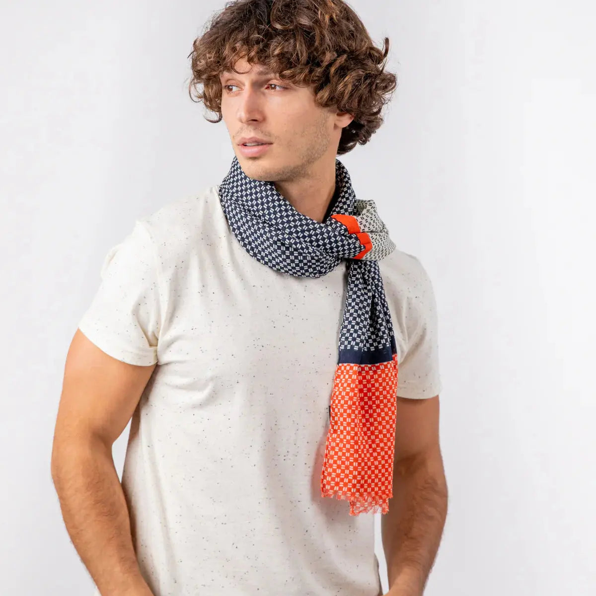 Foulard à semis blanc sur Bleu Marine noué au cou, extrémité orange corail retombant devant le buste