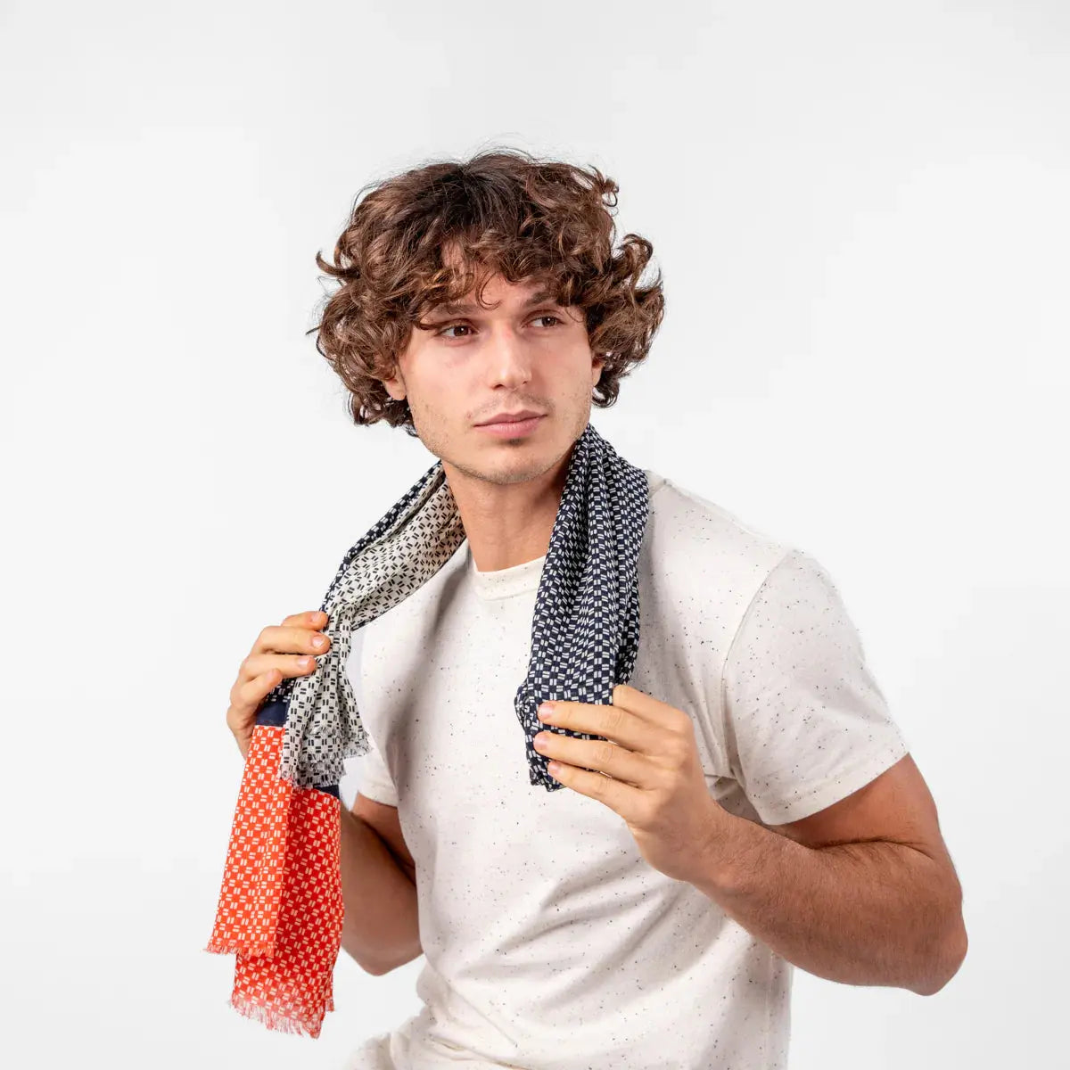 Foulard déplié posé sur les épaules, face Bleu Marine mouchetée et extrémité orange corail frangée