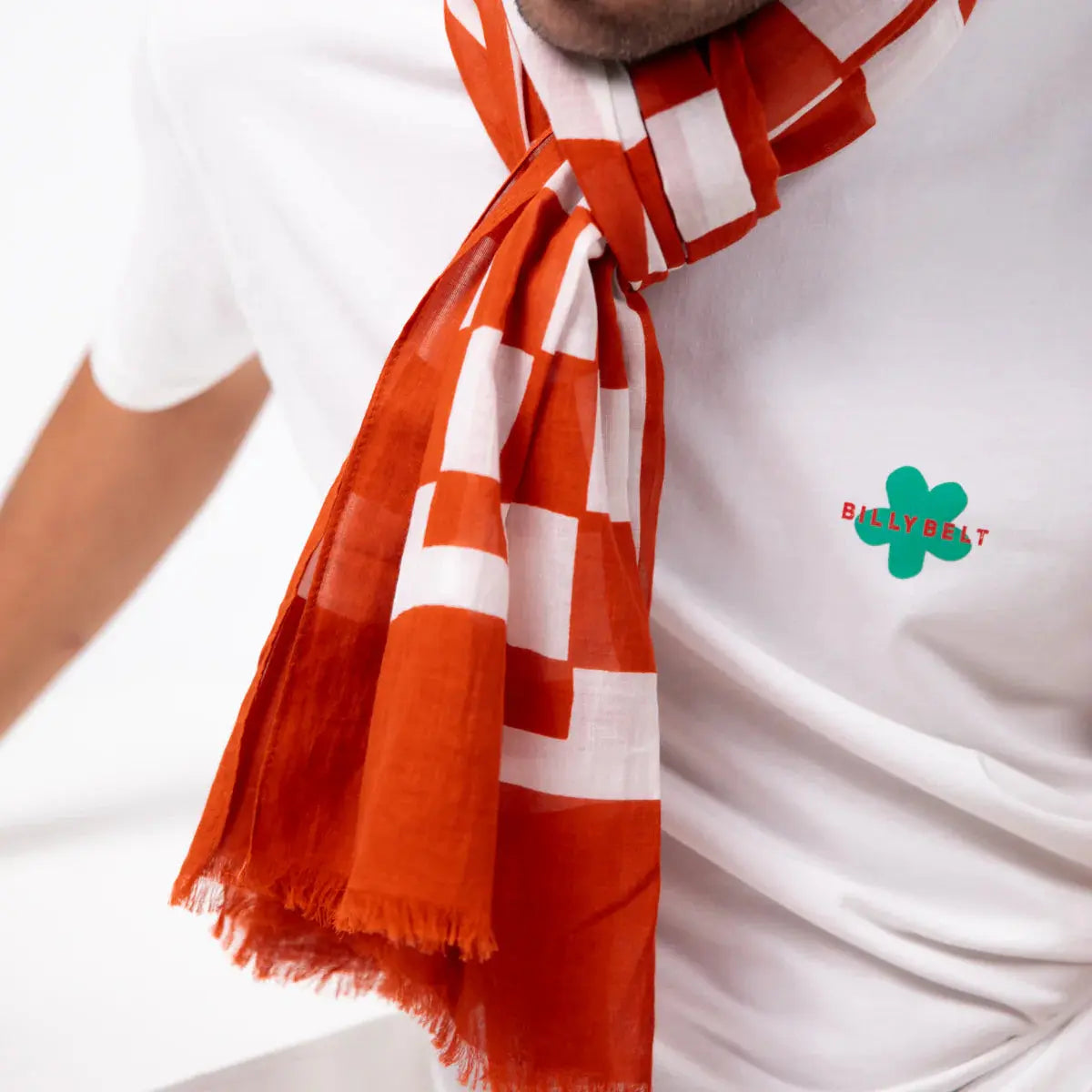 Détail du nœud : damier irrégulier blanc sur orange brique et franges effilochées en bout de pan