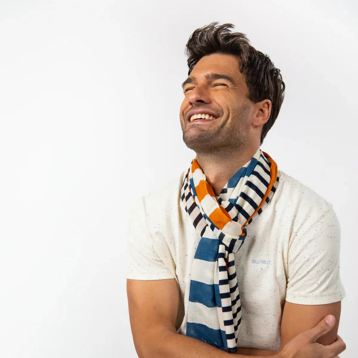 Foulard rayé Bleu Marine et écru noué au cou, touches orange rouille et bleu jean visibles sur les pans