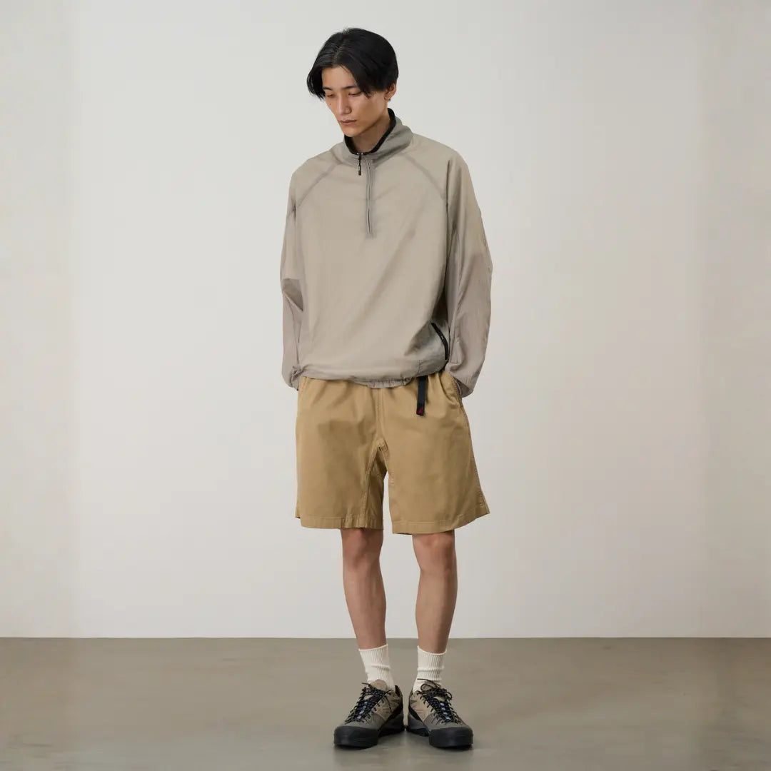 Silhouette complète : G-short beige chino porté avec un pull nylon col zippé et des baskets de randonnée