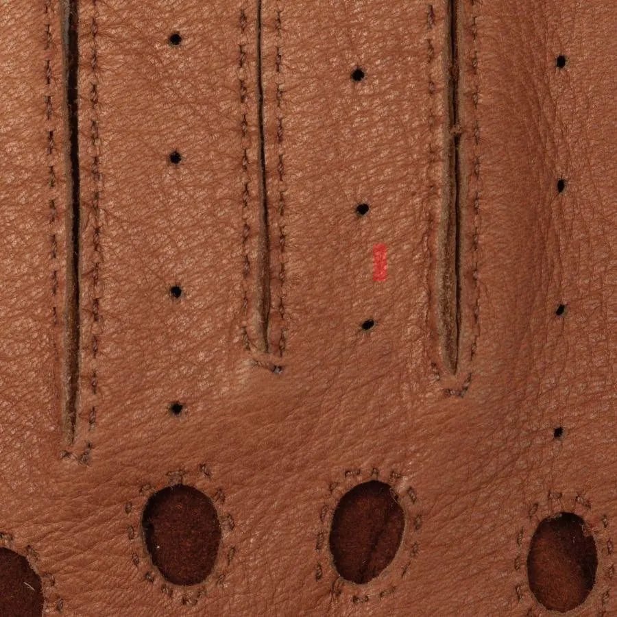 Macro du dos de la main : perforations alignées, nervures et œillets bordés de daim