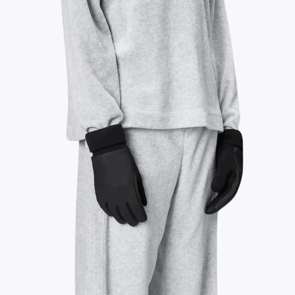 Les deux gants noirs portés le long du corps, paume enduite et bord-côte contrastant
