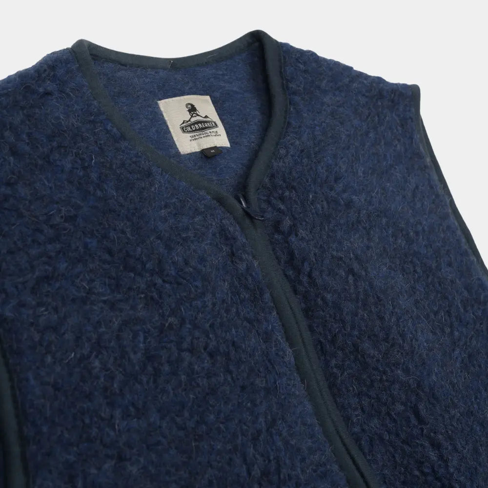 Macro de l'encolure du gilet bleu marine : boucle de laine, étiquette Coldbreaker et biais contrasté