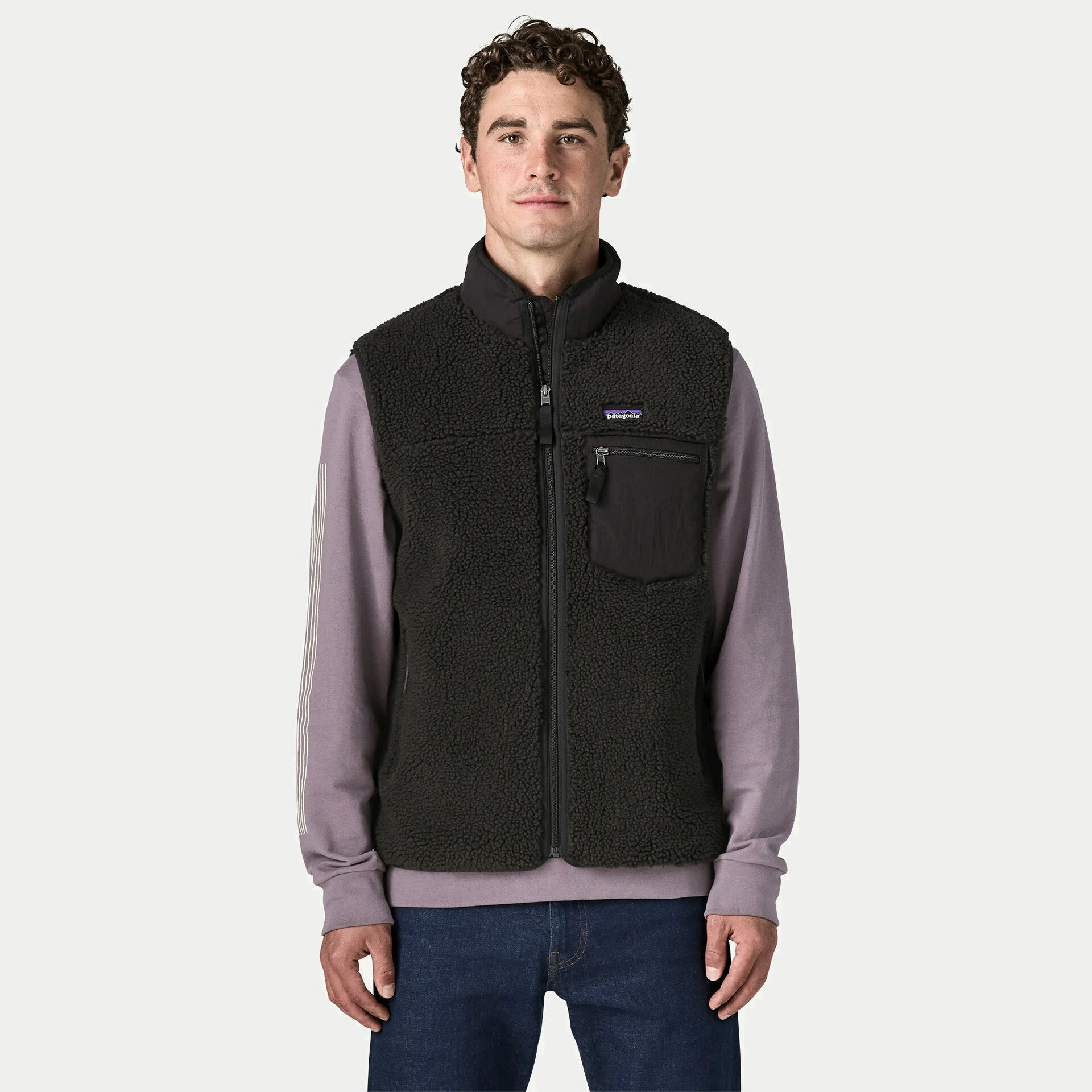 Gilet Retro-X Patagonia noir porté et zippé sur un sweat : col montant doublé, poche poitrine et poches latérales zippées