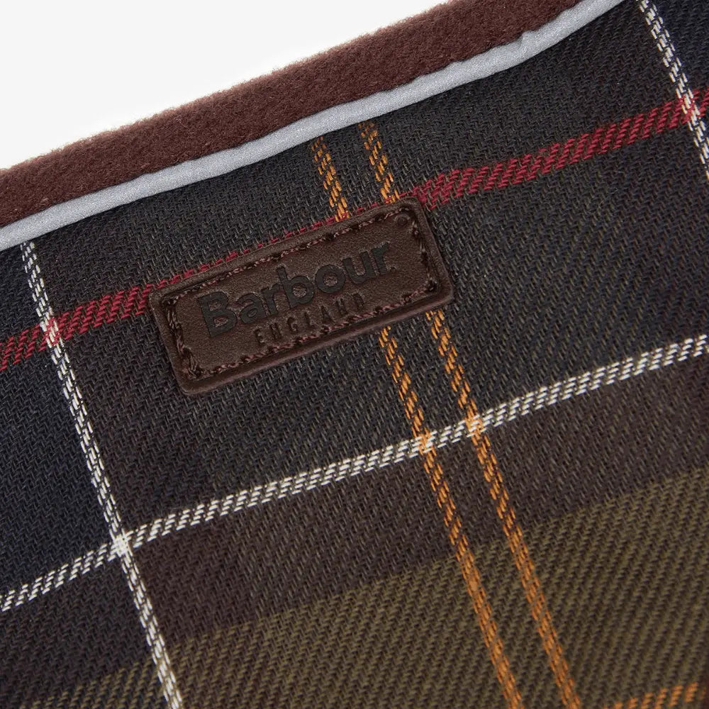 Macro du tartan du harnais : carreaux olive et bleu nuit, lignes rouges, blanches et ocre
