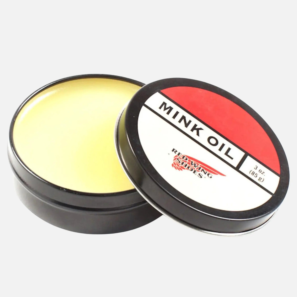 Boîte métal d'huile de vison ouverte sur une pâte jaune pâle, couvercle appuyé sur le côté