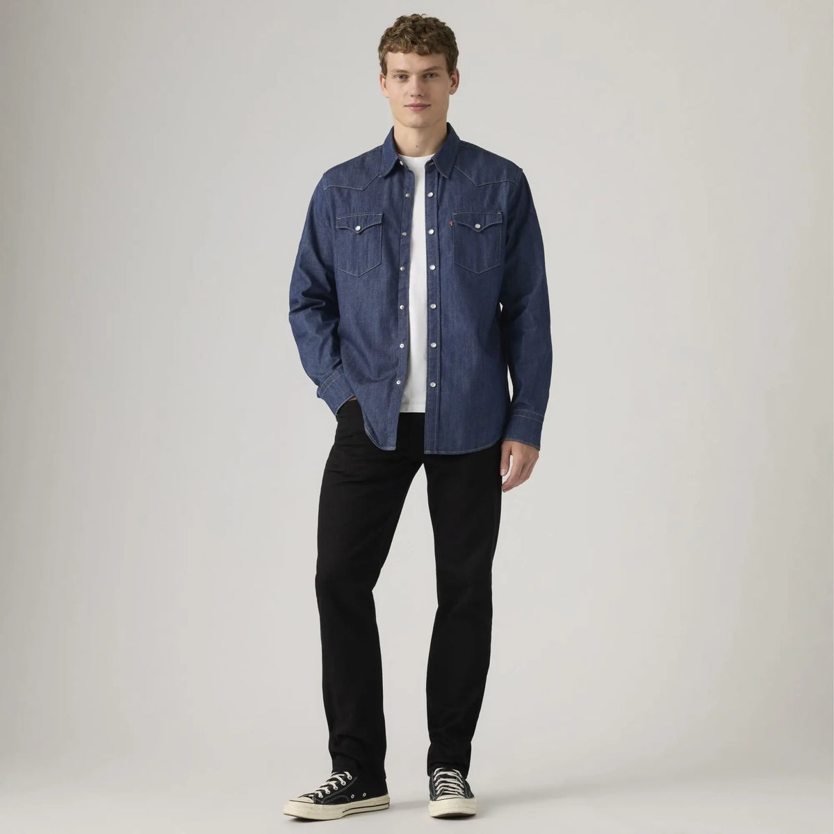 Jean Levi's 502 Taper Sta-Dark Black porté de face avec une chemise western en denim brut et des baskets noires