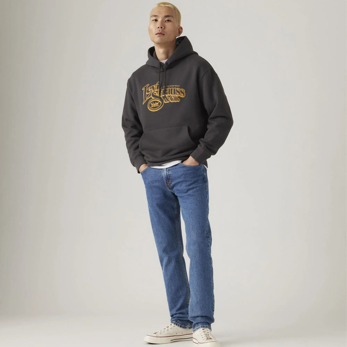 Jean Levi's 502 Taper Stonewash Stretch porté de face avec hoodie gris Levi's Strauss & Co. et baskets blanches