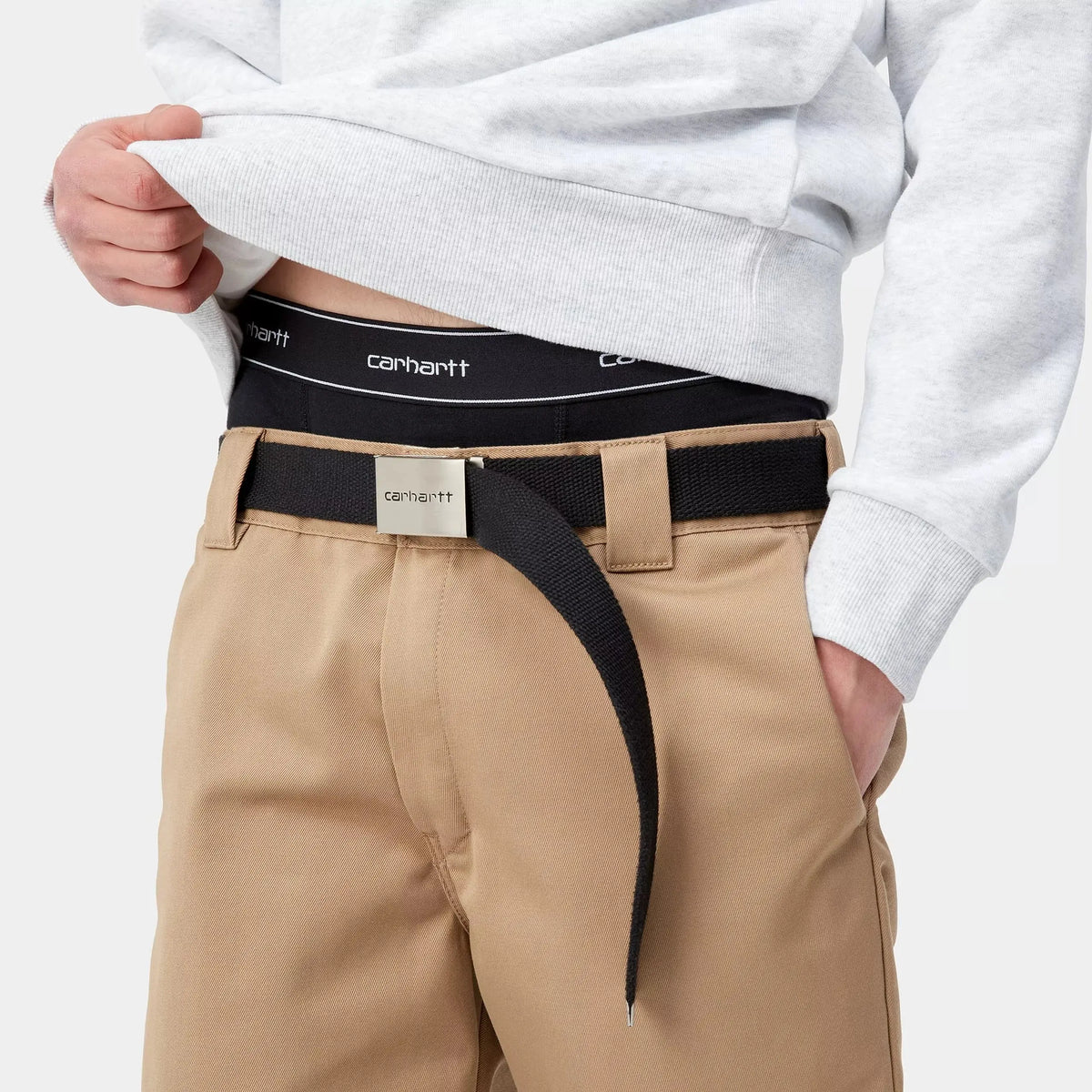 Ceinture élastique noire du boxer porté, visible au-dessus d'un chino beige et d'une sangle noire