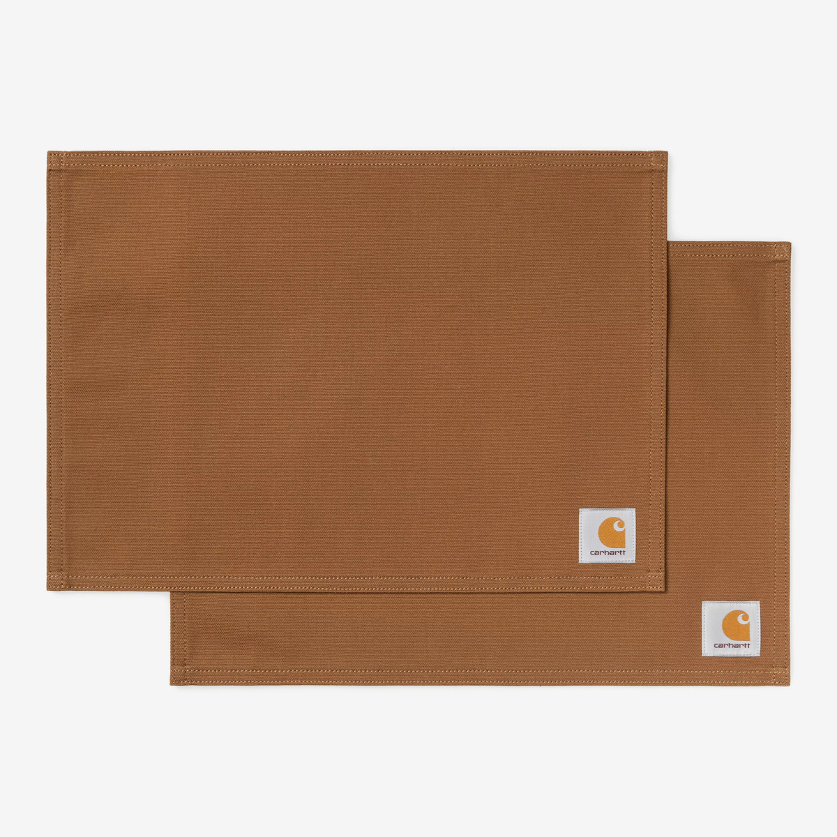 Deux sets de table en toile canvas brun caramel superposés en décalé, surpiqûres au bord et étiquette carrée