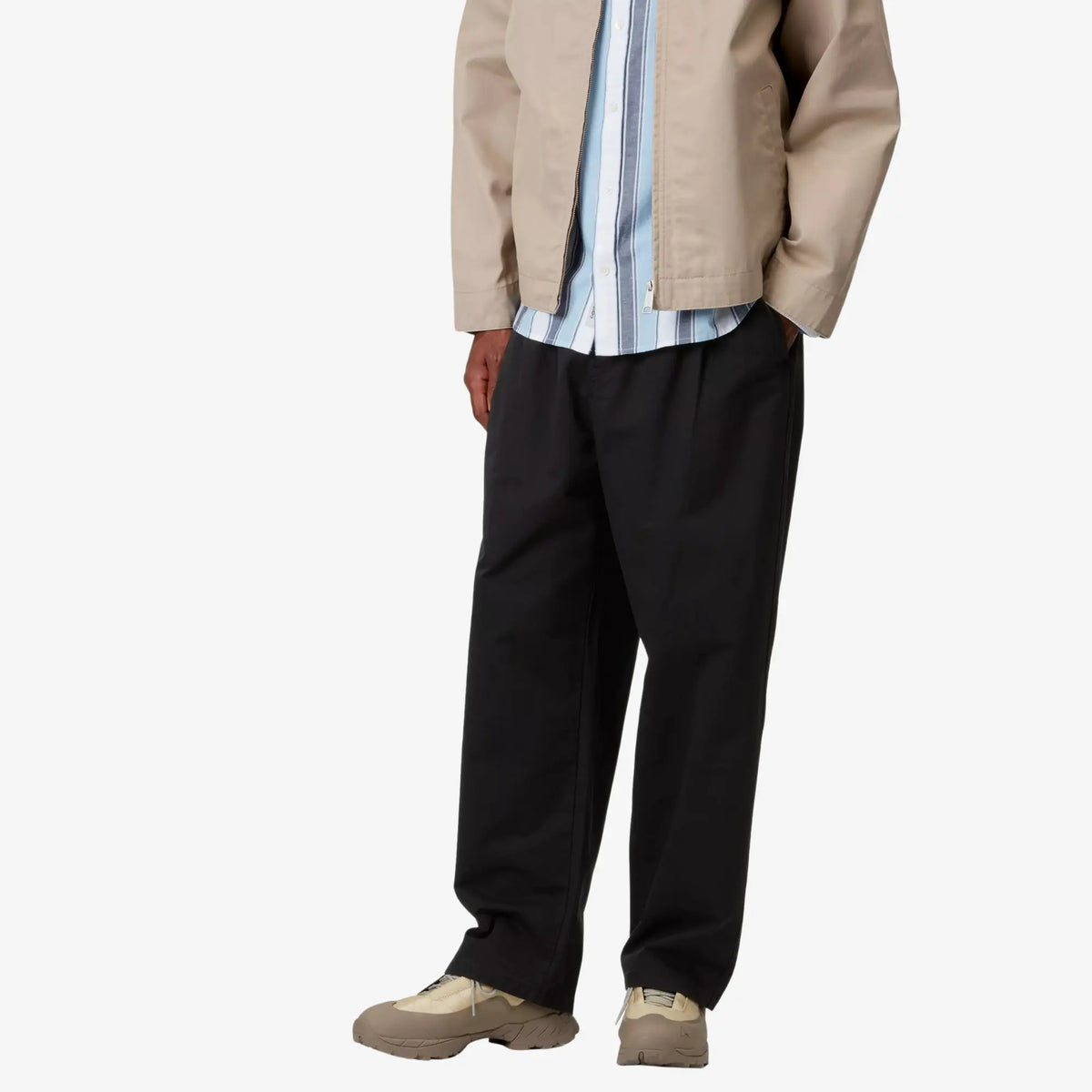 Marv Pant noir porté de profil, main en poche latérale, ligne large et taille montante sans ceinture