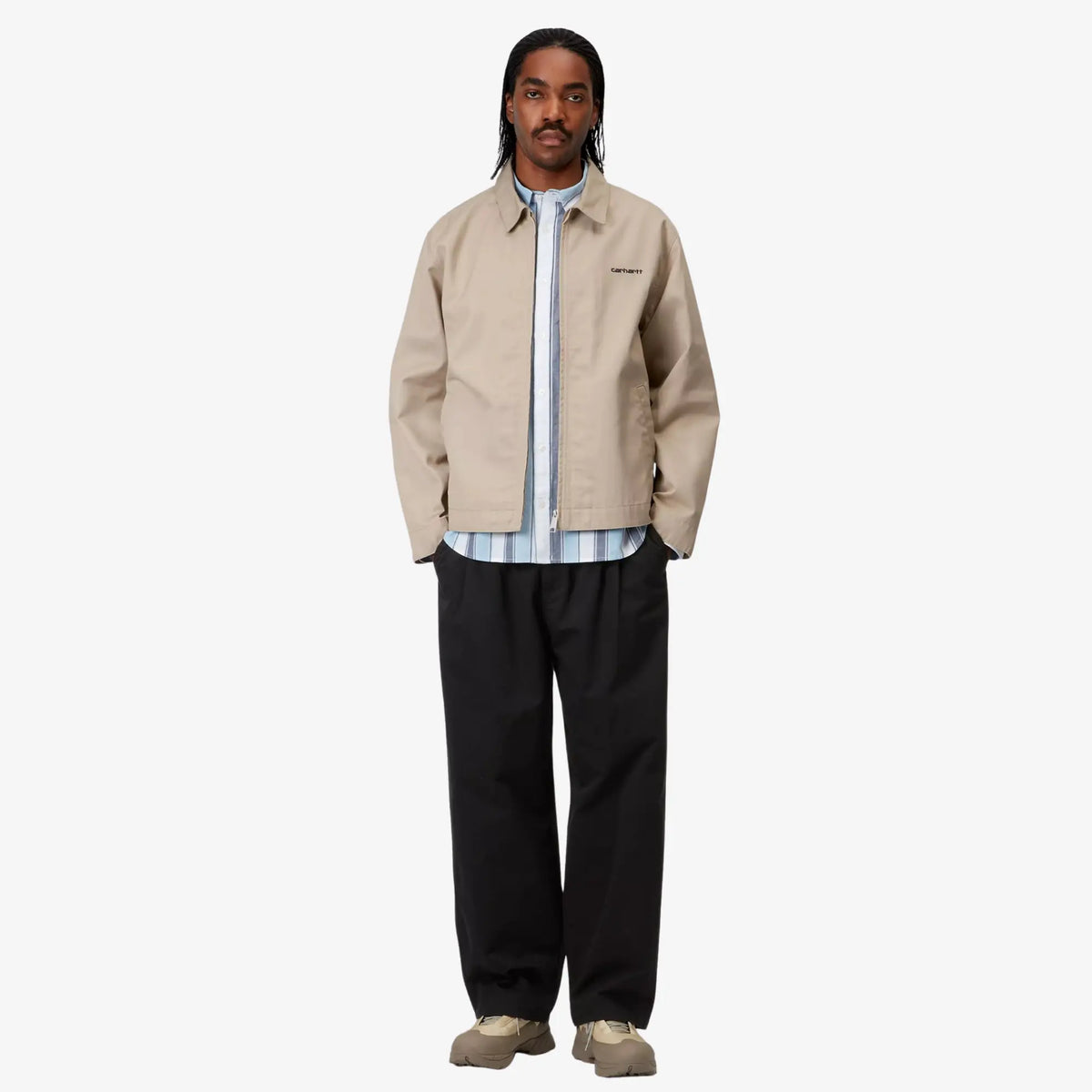 Marv Pant noir porté en pied, vue d'ensemble de la silhouette avec veste beige et chemise rayée bleu clair