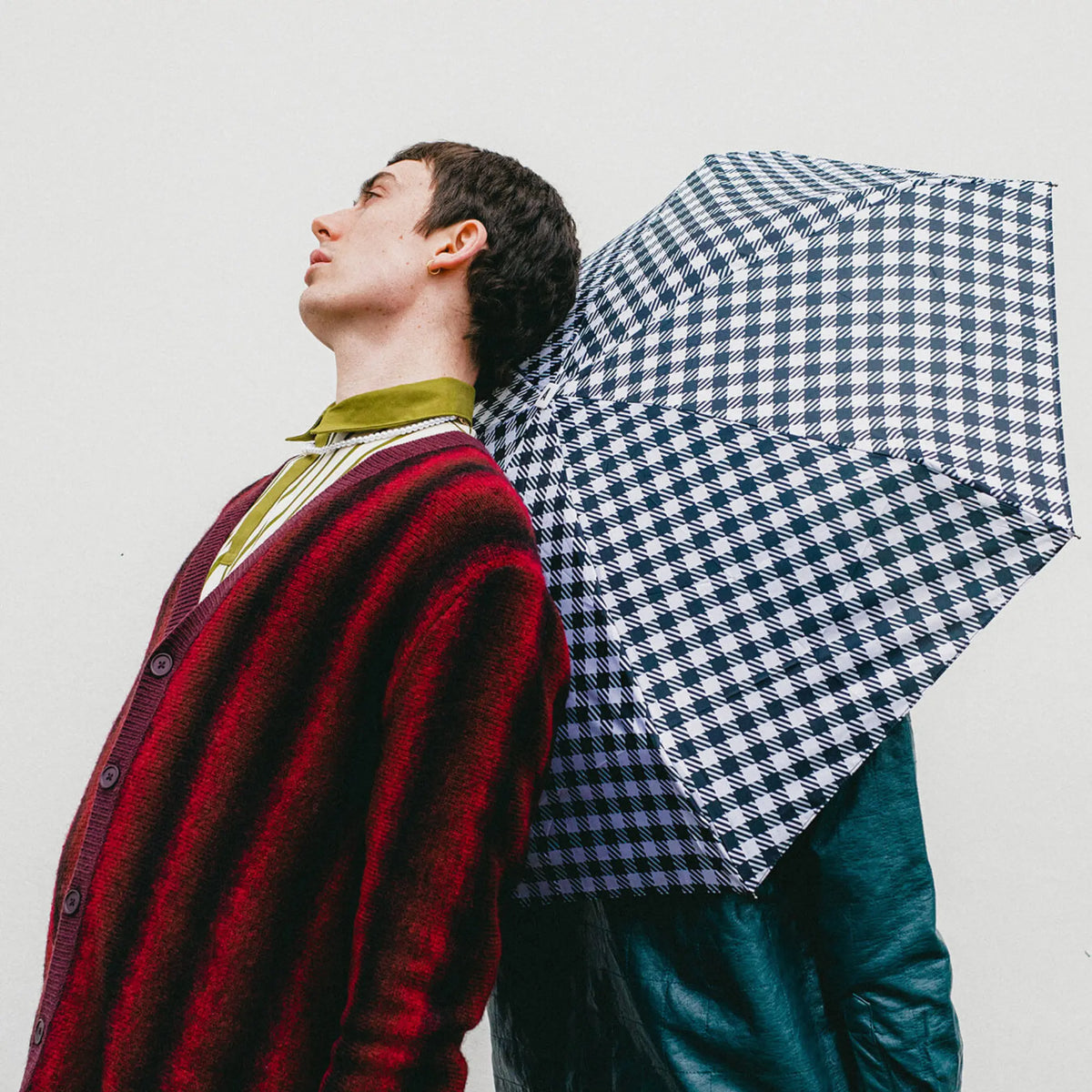 Parapluie Kensington ouvert et porté à l'épaule, gros plan sur le damier vichy noir et blanc