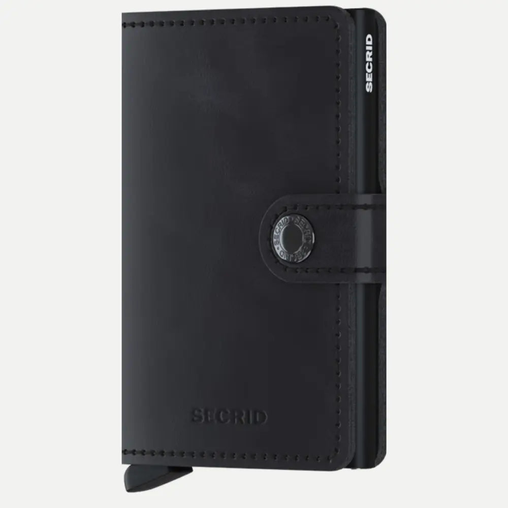 Petit portefeuille en cuir noir vieilli mat, fermé par sa patte à bouton pression