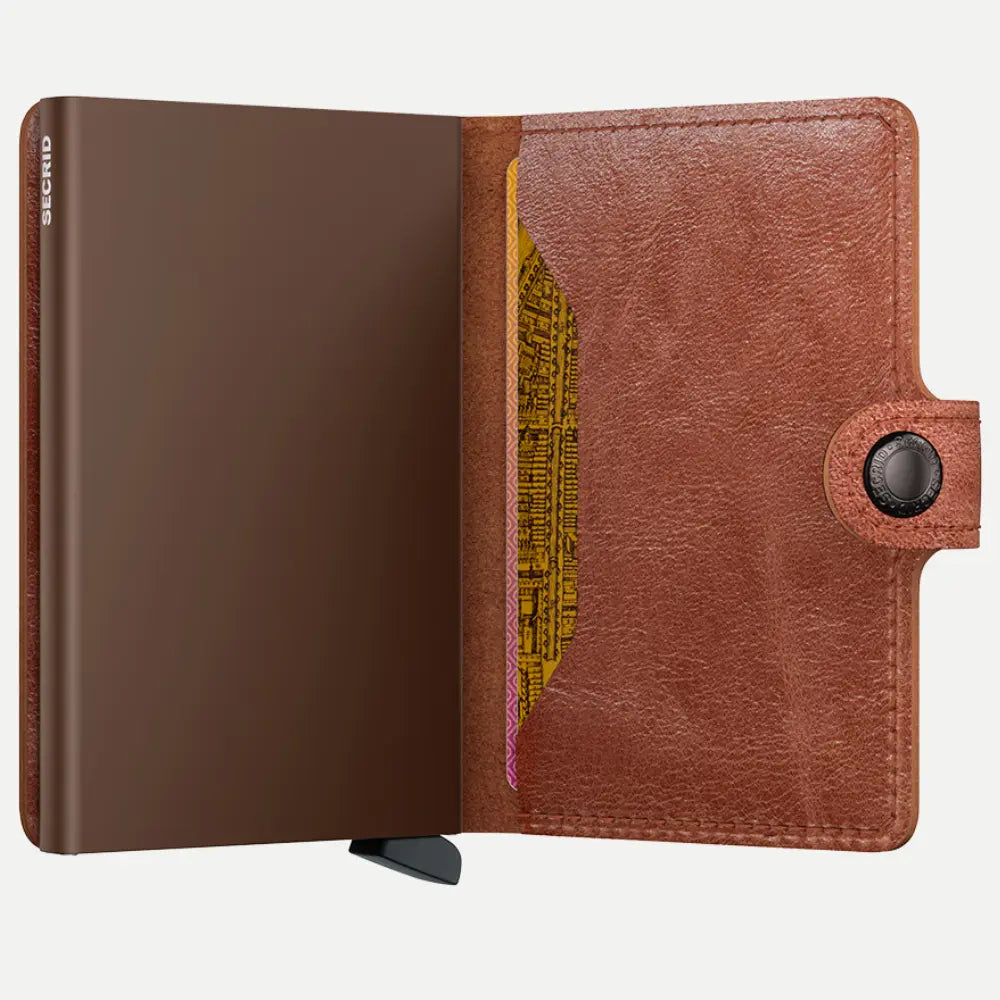 Portefeuille cognac ouvert, boîtier brun bronze et carte jaune glissée dans le rabat