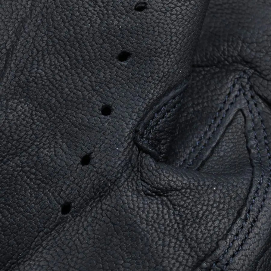 Macro du grain du cuir bleu marine et des perforations alignées le long des doigts