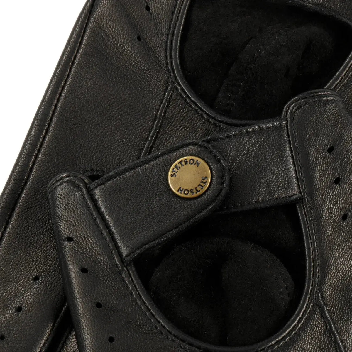 Gros plan du bouton-pression laiton gravé Stetson sur la patte de poignet noire