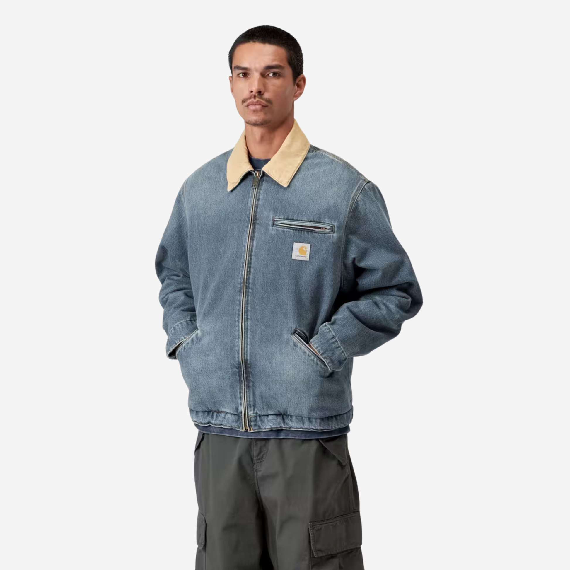 Veste OG Detroit Carhartt WIP en denim bleu portée fermée de trois quarts, mains dans les poches passepoilées