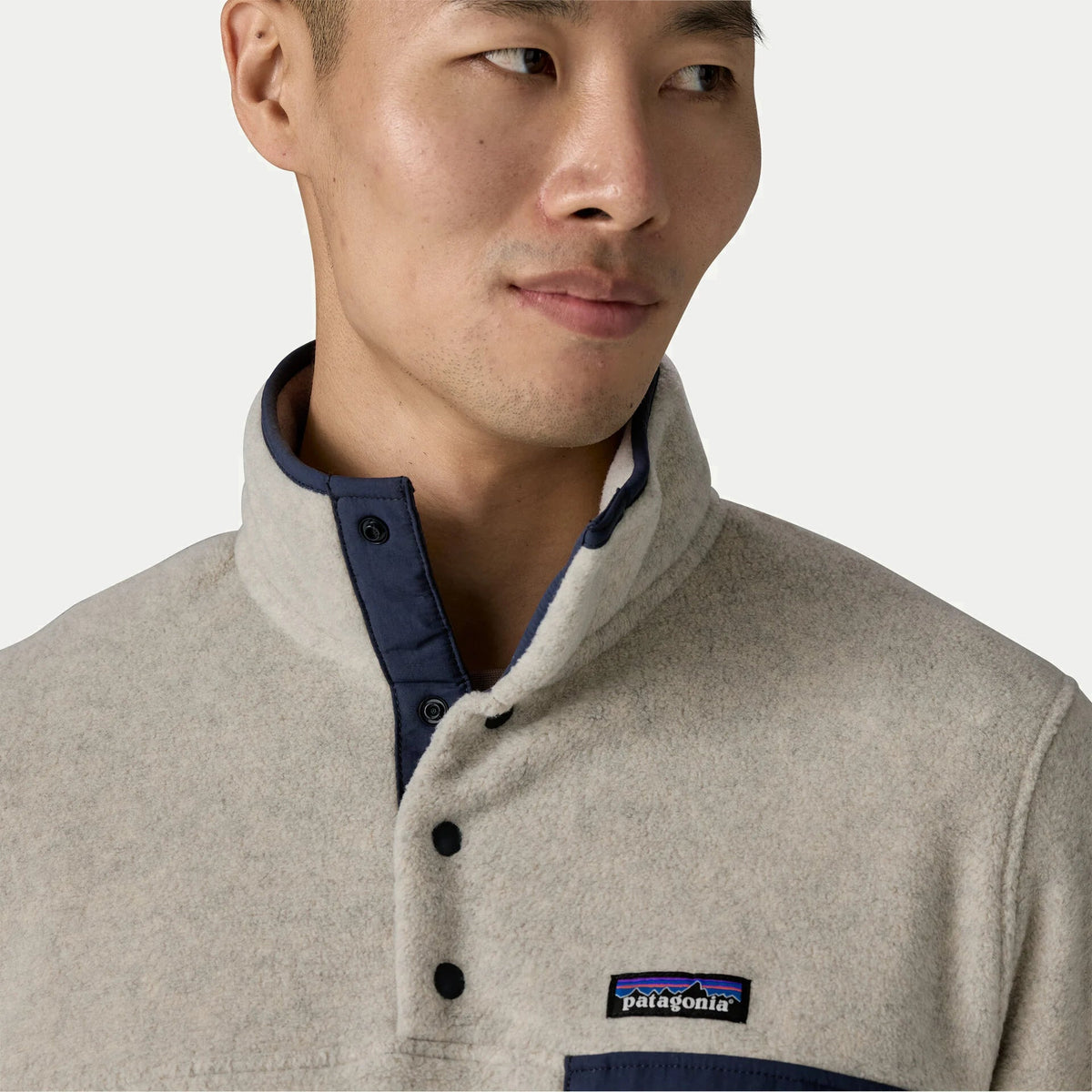 Détail du col montant de la polaire Snap-T Patagonia : patte nylon marine à pressions et étiquette de marque