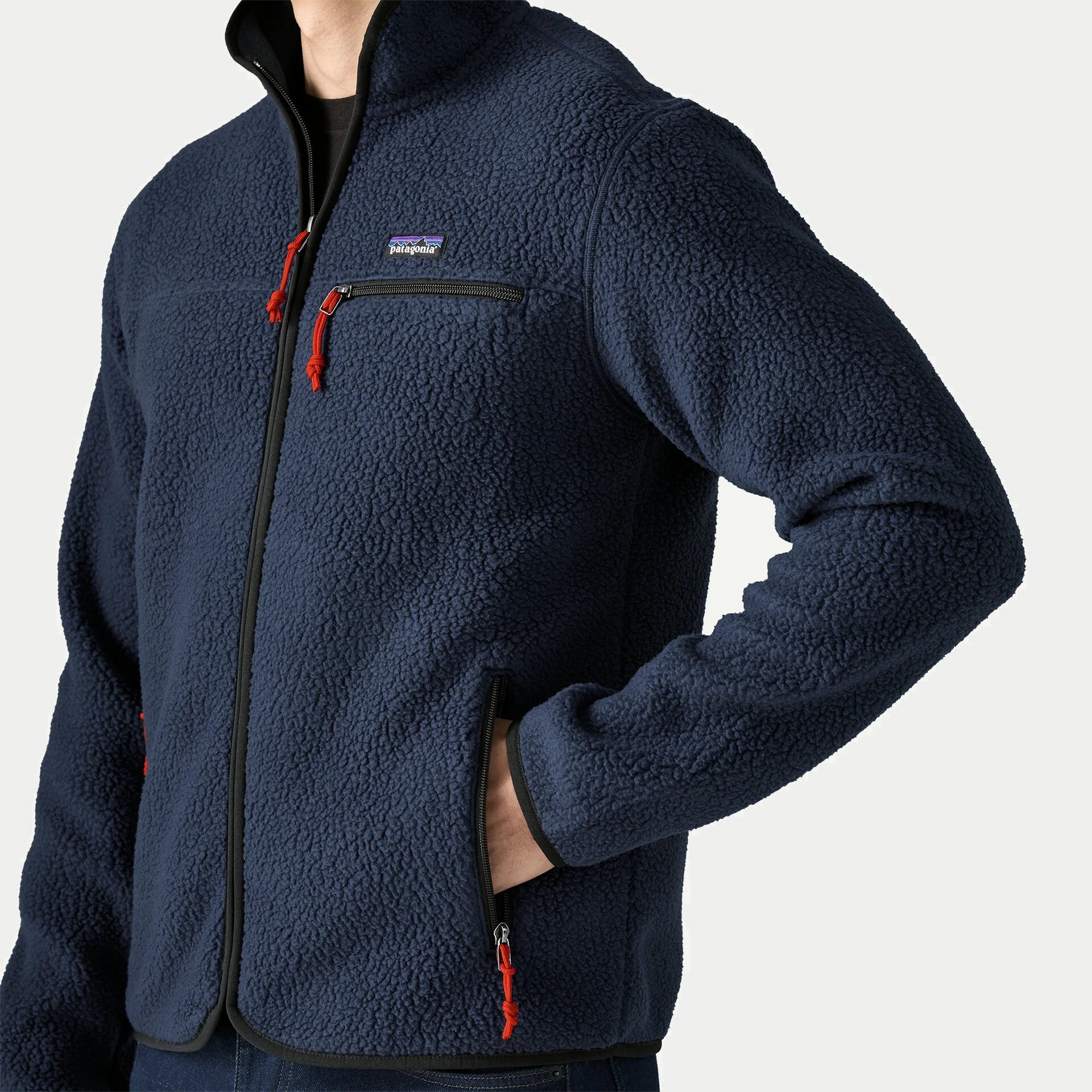 Gros plan sur le sherpa bouclette marine de la polaire Retro Pile Patagonia, étiquette logo et poche poitrine zippée