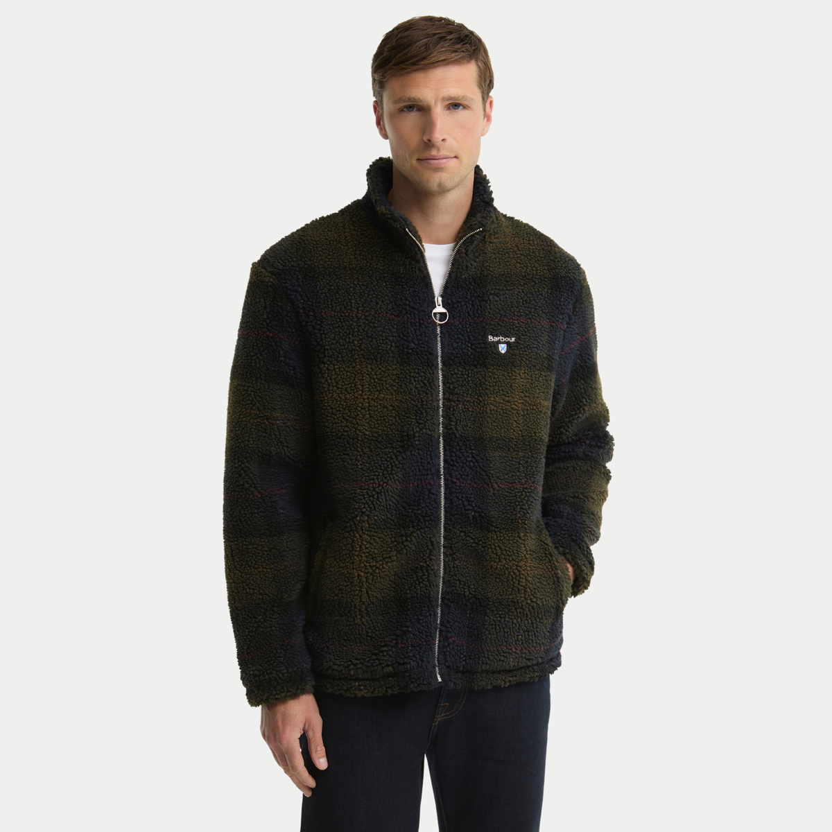 Polaire sherpa Barbour tartan olive foncé portée, zip entrouvert sur t-shirt blanc, une main en poche