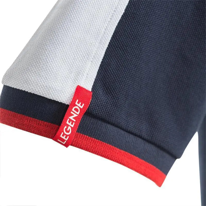 Détail du bas de manche du polo, bordure côtelée bleu marine et rouge et étiquette rouge Legende