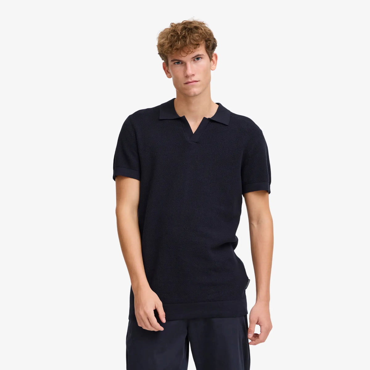 Polo bleu marine porté, col ouvert en V et maille texturée, associé à un pantalon bleu marine