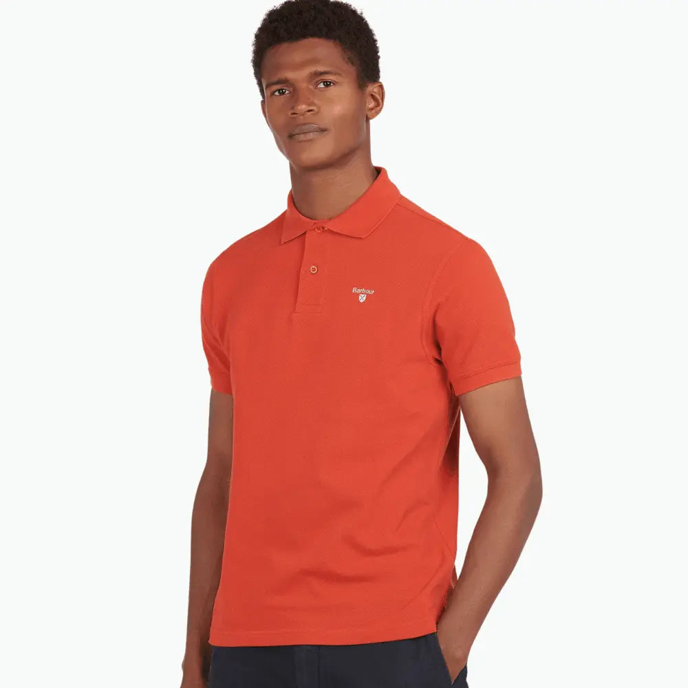 Polo Paprika porté de trois-quarts, piqué orangé et logo brodé blanc sur la poitrine