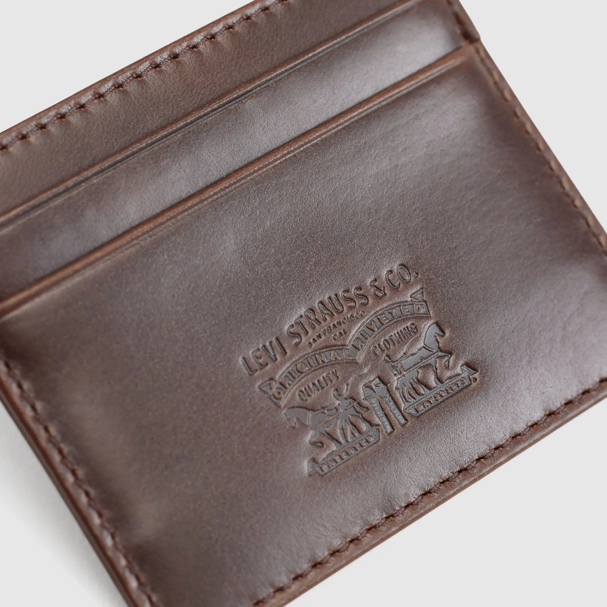 Gros plan sur le cuir lisse marron et l'embossage two horse du porte-cartes Levi's