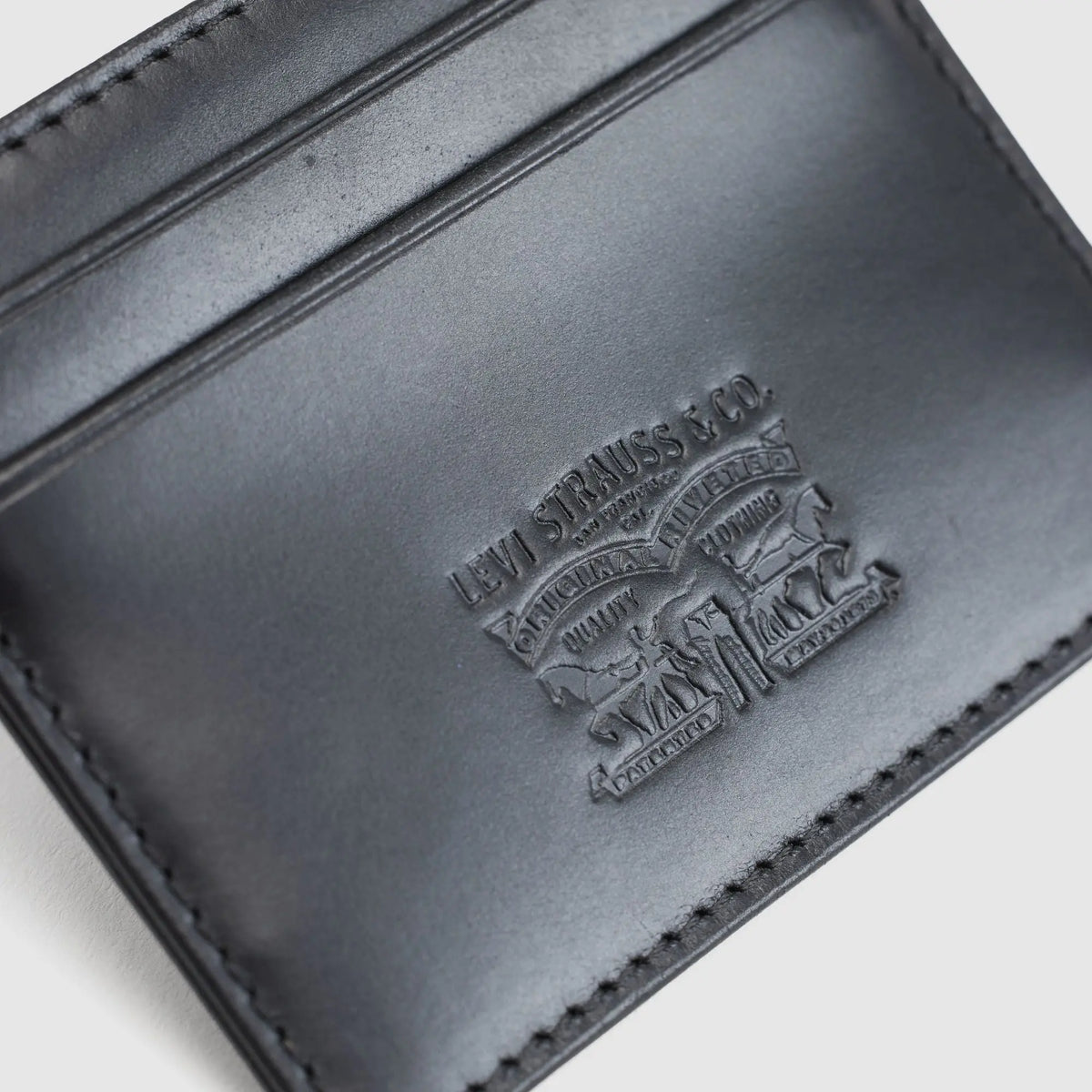 Gros plan sur le logo Two Horse Levi Strauss & Co. embossé dans le cuir noir du porte-cartes