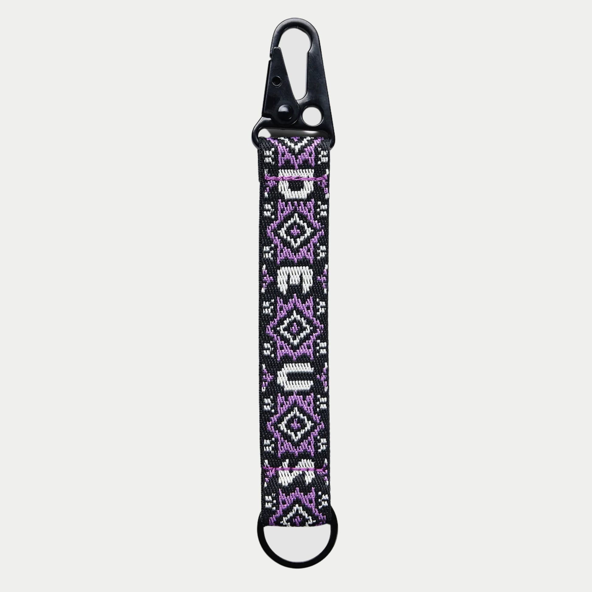 Porte-clés Utah : sangle noire, jacquard losanges lilas et blancs, lettrage DEUS vertical, mousqueton à ressort, anneau en D
