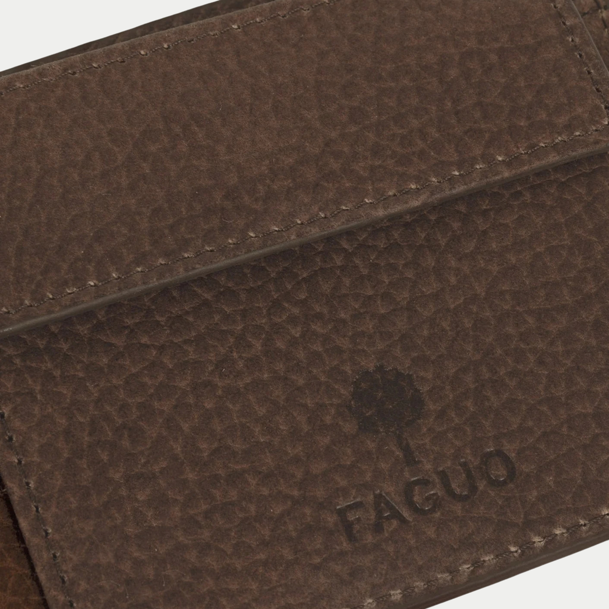 Détail macro du cuir grainé et du logo arbre FAGUO embossé sur le portefeuille marron