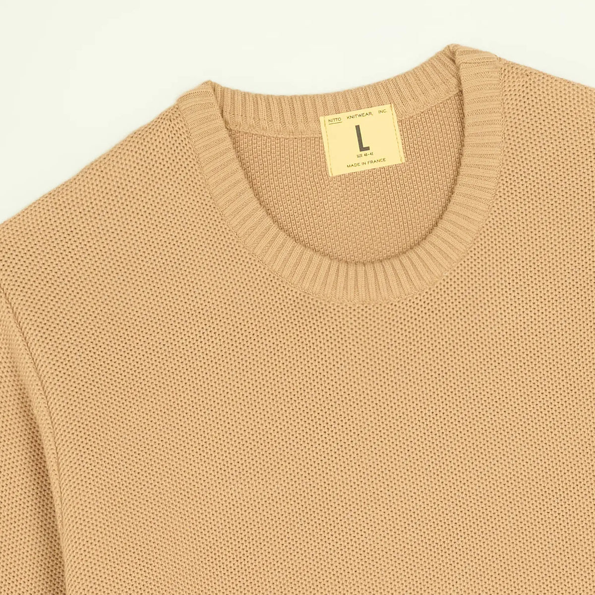 Détail du col rond côtelé du Pull Agop camel, étiquette jaune Nitto et grain de la maille coton