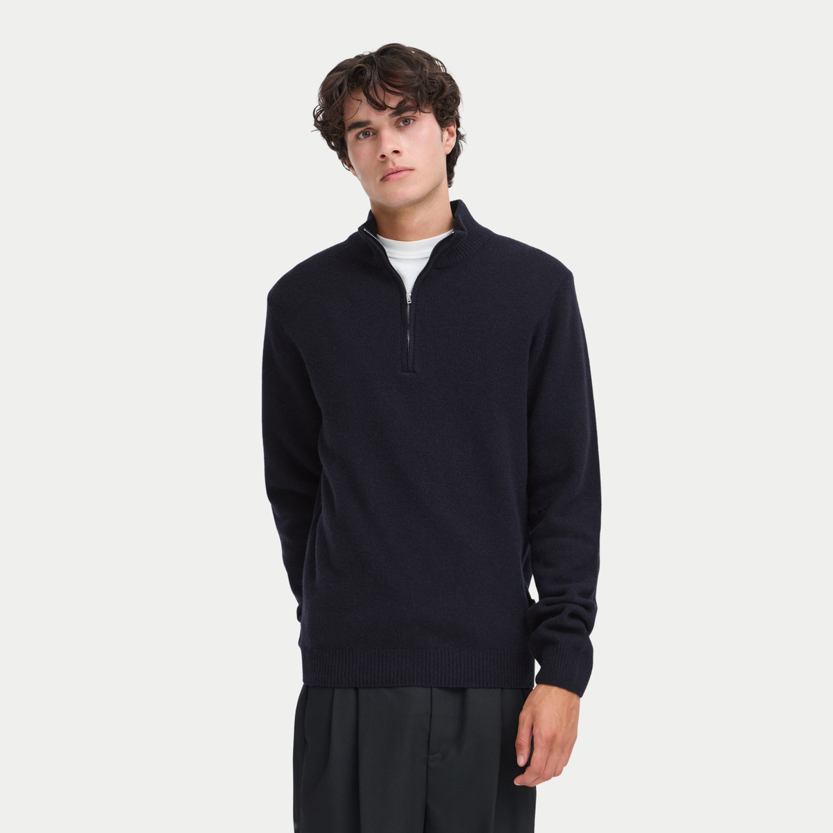 Pull half zip bleu marine porté de face, col zippé ouvert sur un t-shirt blanc