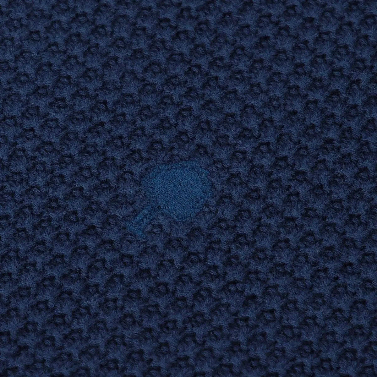 Macro de la maille texturée bleu marine du Lucio et de sa broderie arbre bleu vif