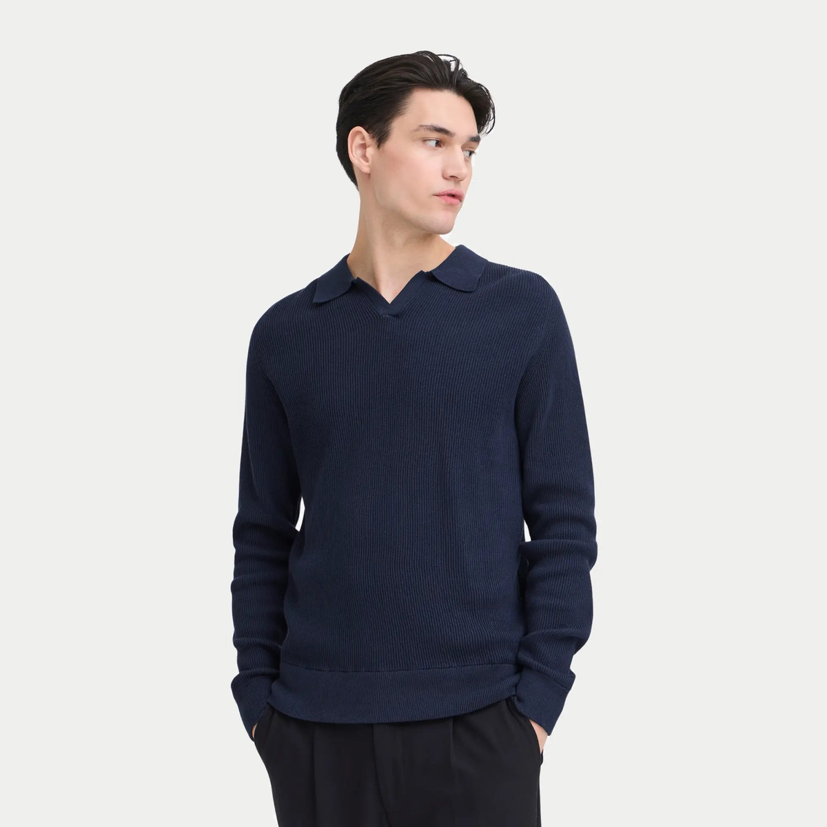 Pull polo bleu marine porté avec un pantalon noir, bord-côte de taille et poignets larges