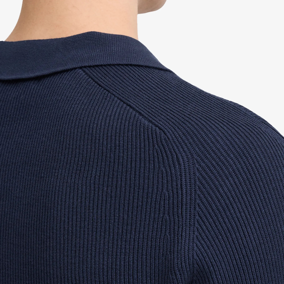 Détail d'épaule du pull polo bleu marine : couture raglan et côtes fines de la maille