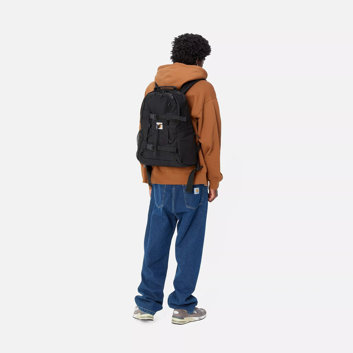 Sac à dos Kickflip noir porté sur le dos, poche latérale en filet et sangles libres qui pendent le long