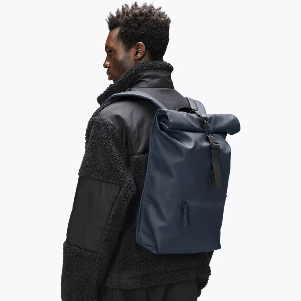 Rolltop Rucksack Bleu Marine porté sur le dos, volume compact et boucle de fermeture noire