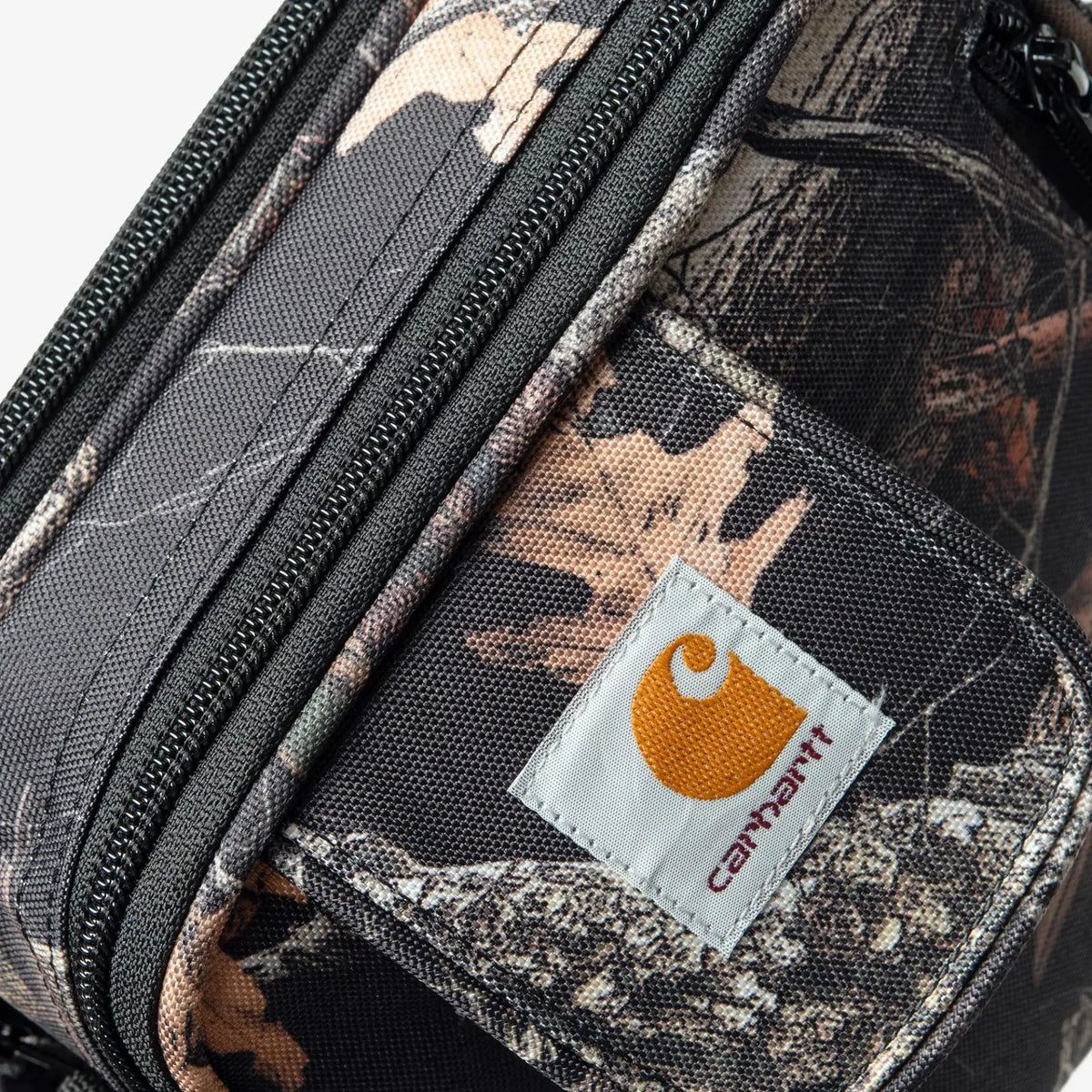 Sacoche Essentials Bag Camo Feather Tree Carhartt WIP - détail de la toile camouflage, zips et étiquette logo
