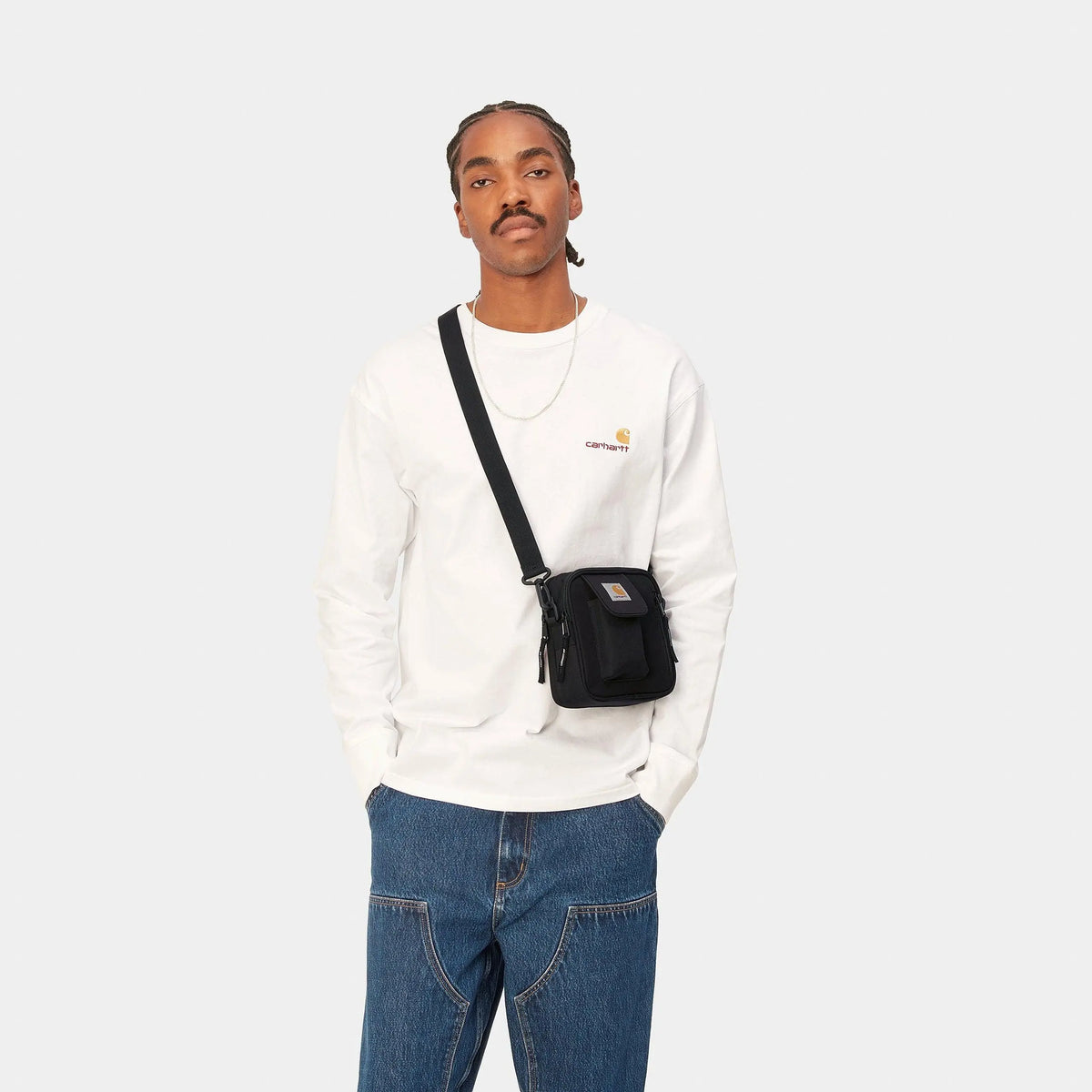 Sacoche Essentials Bag Black Carhartt WIP portée en bandoulière croisée sur un t-shirt manches longues blanc