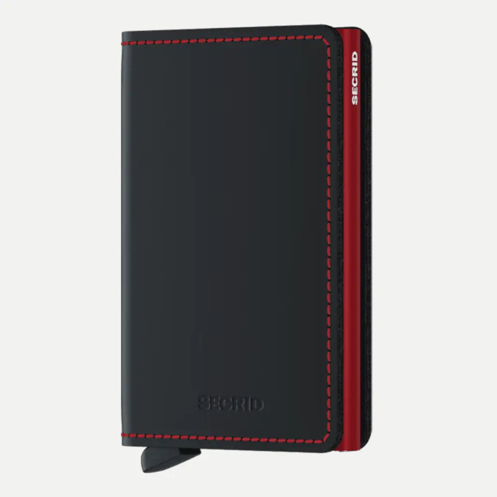 Portefeuille plat en cuir noir mat à surpiqûres rouges, boîtier rouge visible sur la tranche