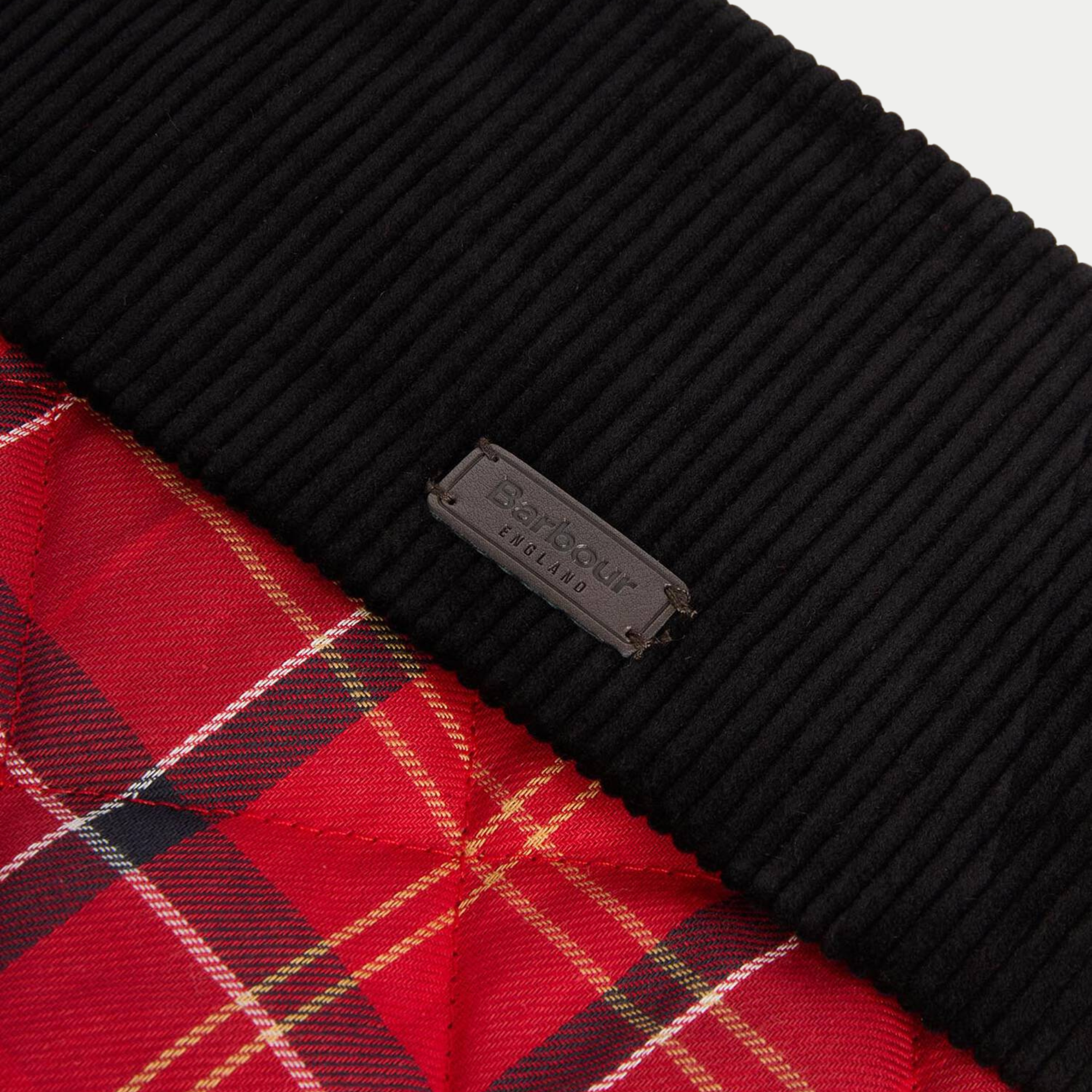 Détail de la plaque logo Barbour England embossée sur le revers de velours côtelé noir de la chaussette de Noël