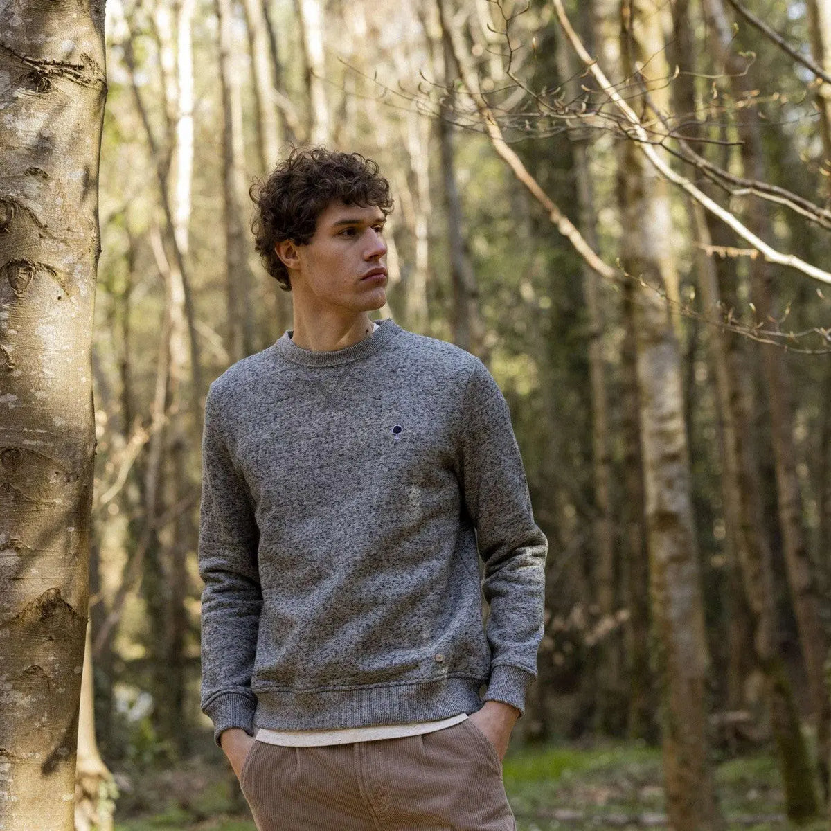 Sweat Donon gris chiné porté de face en forêt, avec un pantalon velours beige