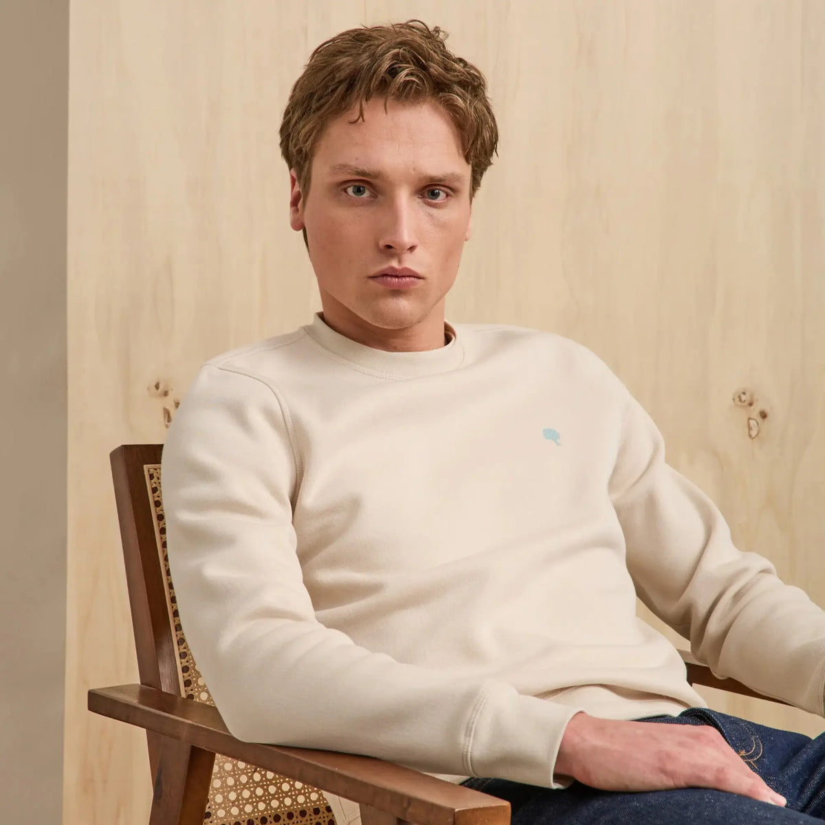 Sweat Donzy beige porté assis, manches longues tombant droit sur un jean brut