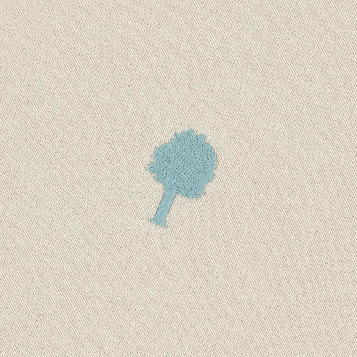 Macro de la broderie arbre bleu ciel sur le molleton beige du Donzy