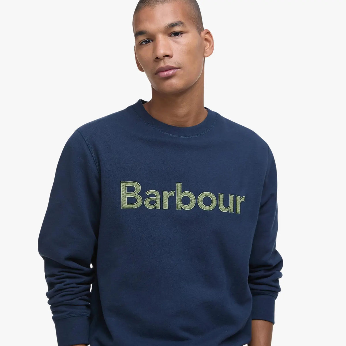 Gros plan du lettrage brodé vert sur la maille bleu marine du sweat