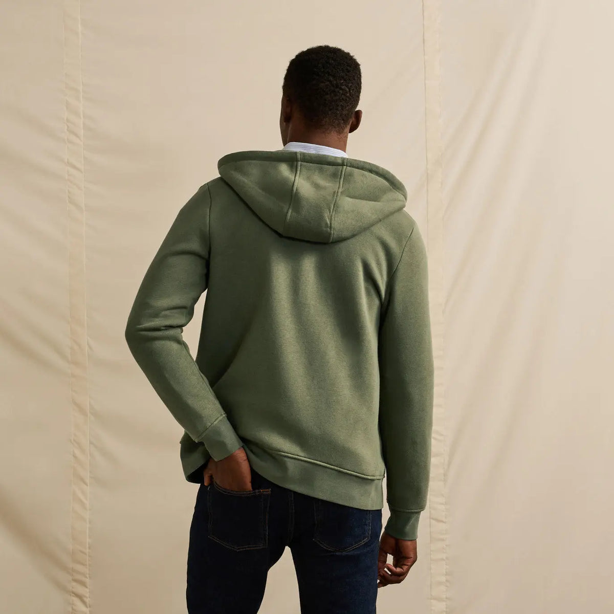 Dos du sweat zippé kaki porté : capuche retombante, dos uni et bas de corps resserré par une bande côtelée