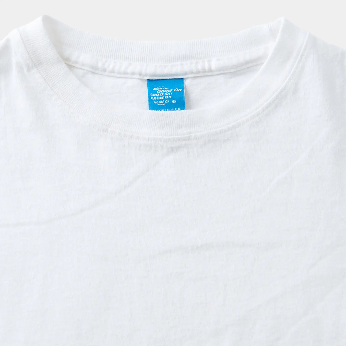 Encolure du T-shirt Good On blanc en gros plan, étiquette de marque tissée bleue